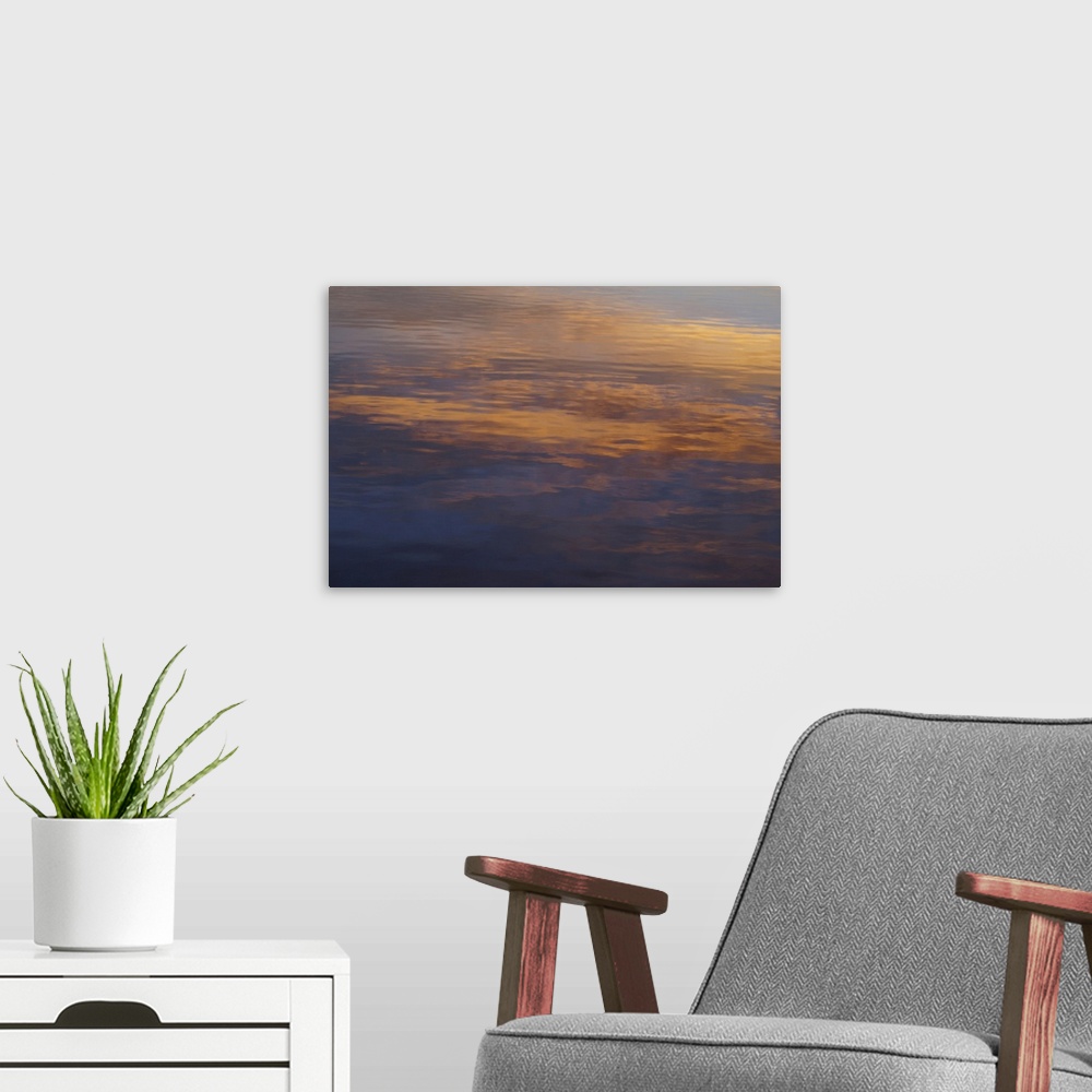 A modern room featuring Clouds lit by the setting sun, look at their reflections in the water.