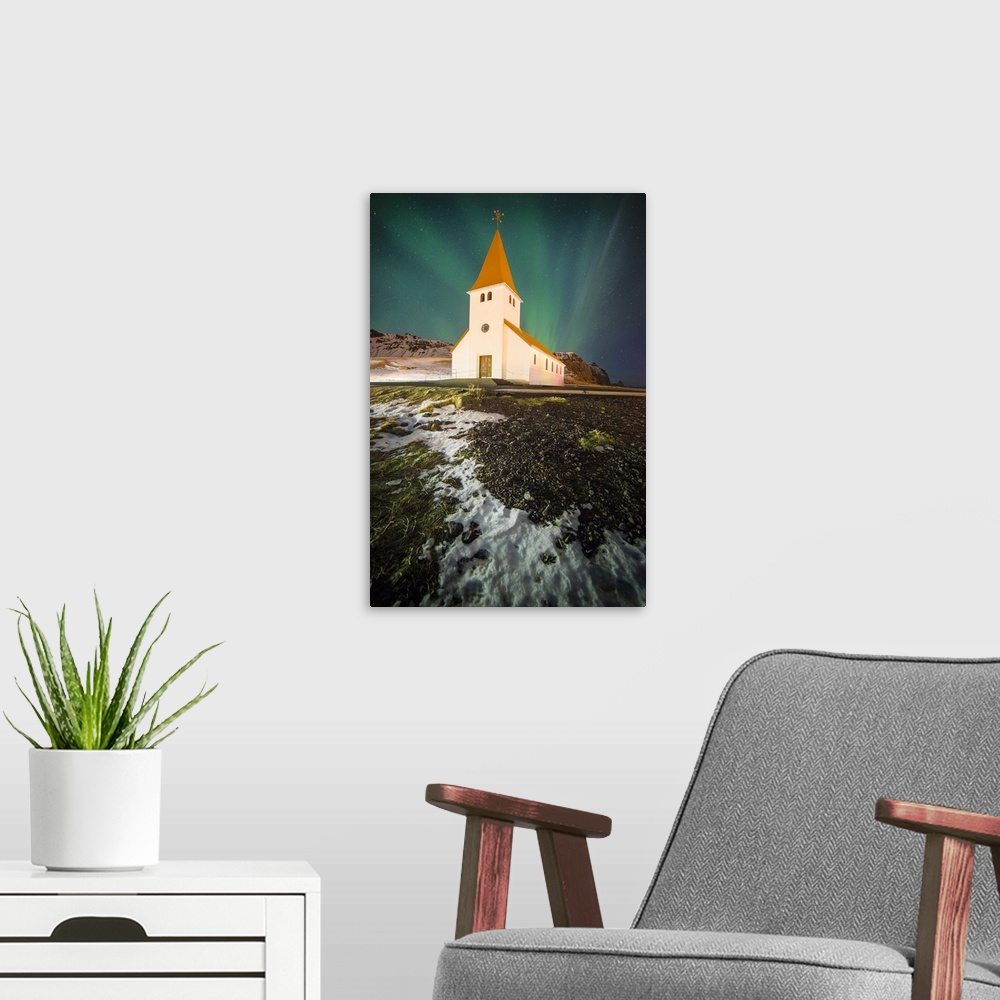 A modern room featuring Northern lights in the sky over a church in Vik i Myrdal, Iceland, at night.