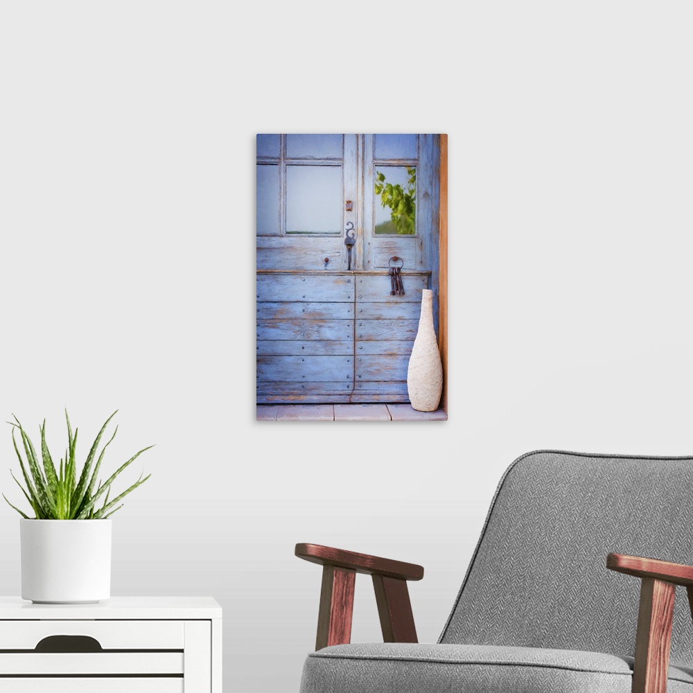A modern room featuring A photograph of a tall vase sitting in front of a blue cottage door.