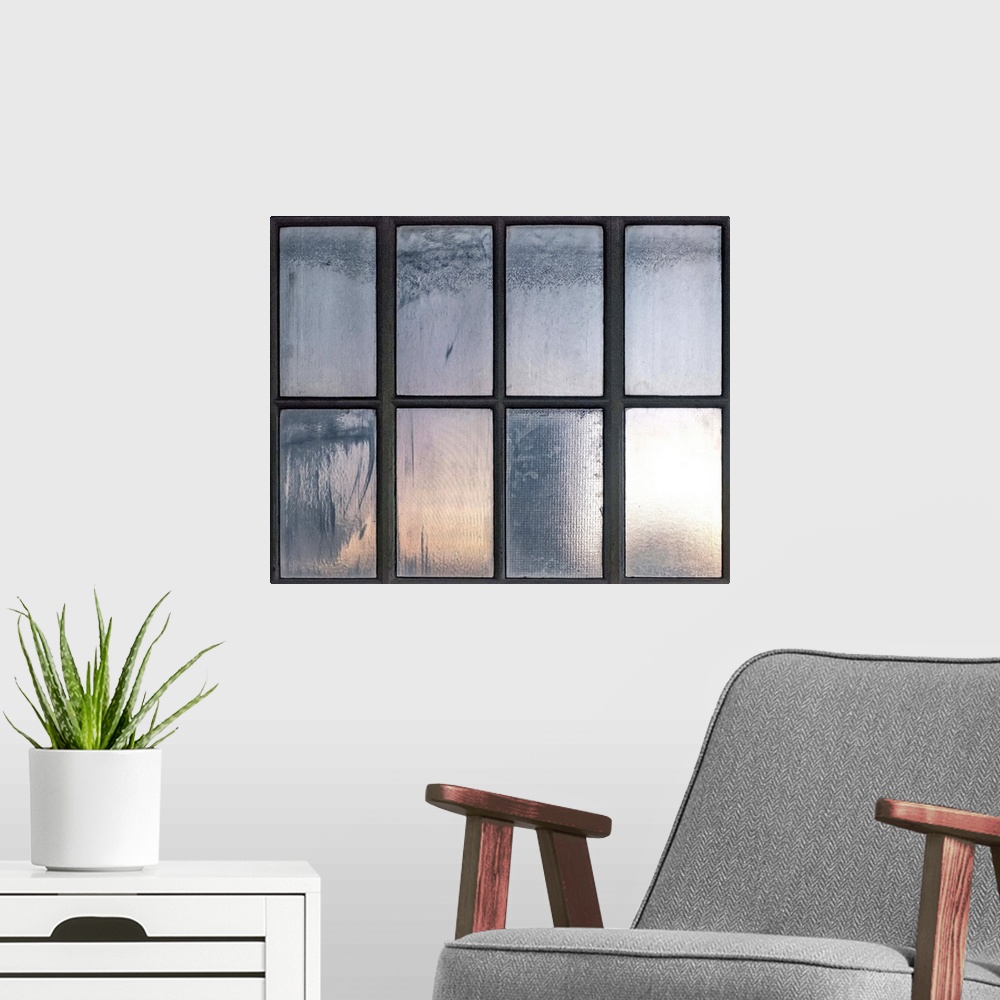 A modern room featuring A photograph of a window with rectangular panes with low light shining through.