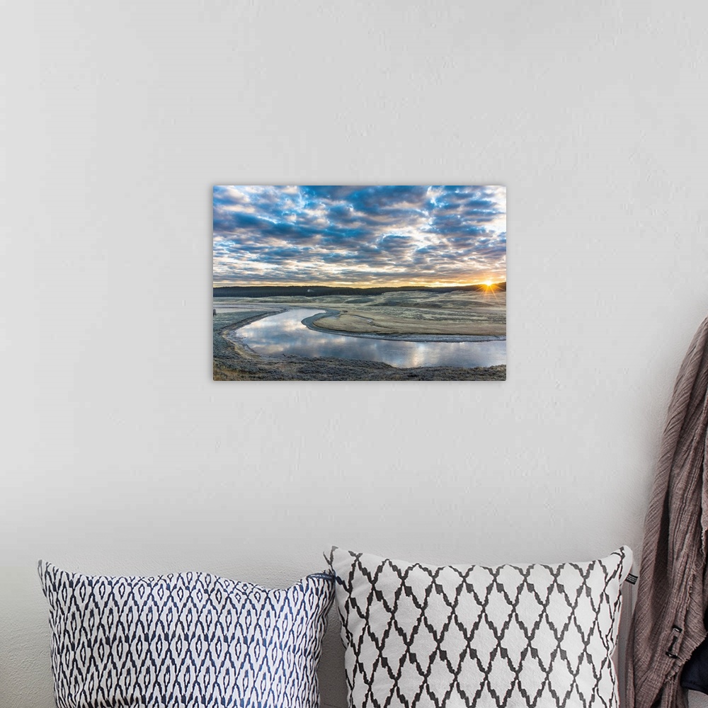 A bohemian room featuring Fine art photograph of the sun on the horizon by the Yellowstone River with cloudy skies above.