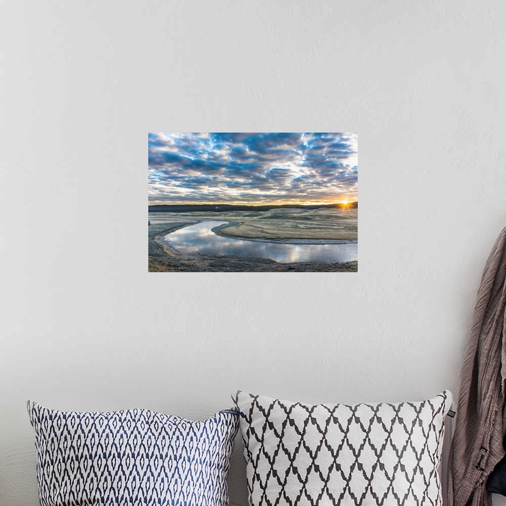 A bohemian room featuring Fine art photograph of the sun on the horizon by the Yellowstone River with cloudy skies above.