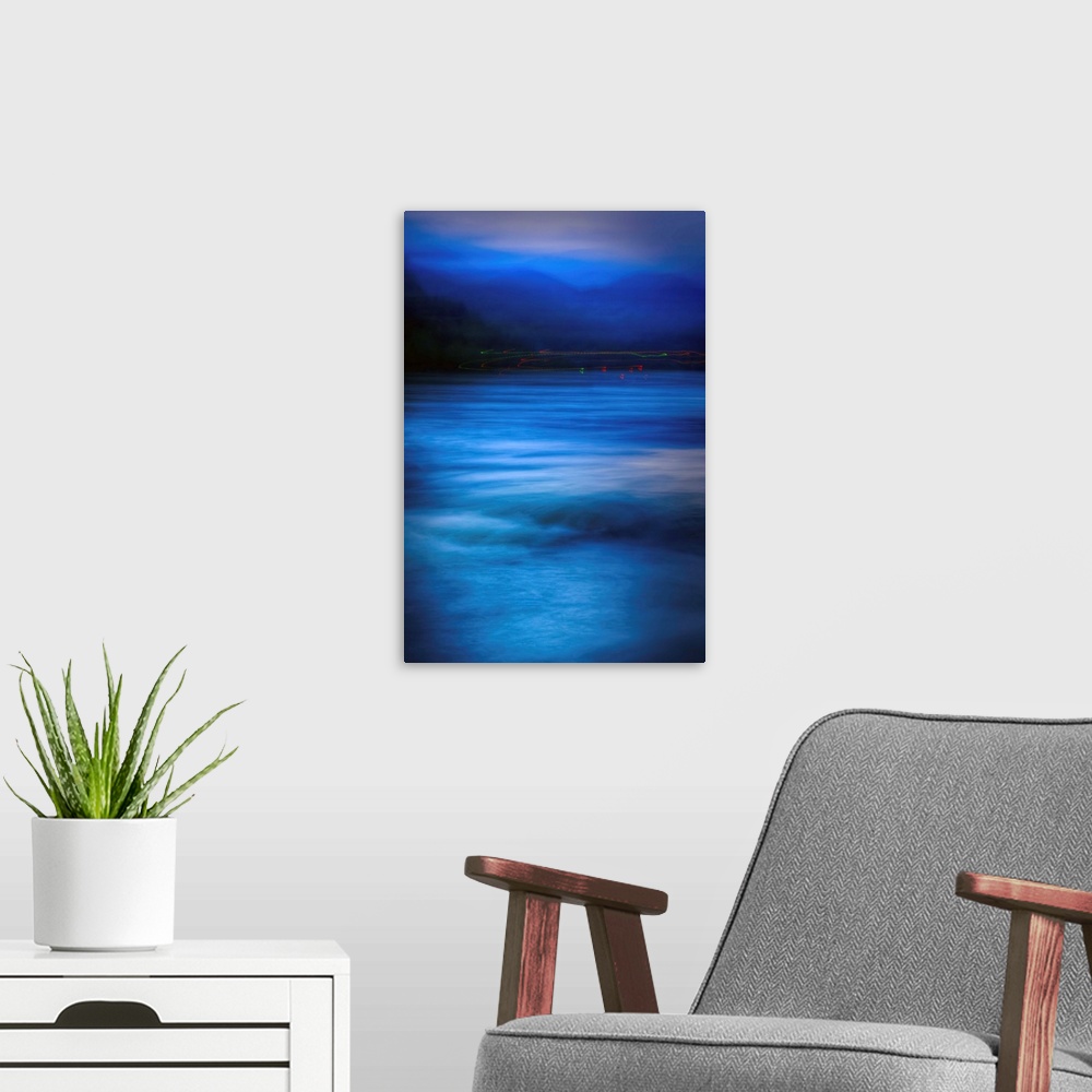 A modern room featuring A large vertical piece with majestic blue waters below and the silhoutte of the forest and mounta...
