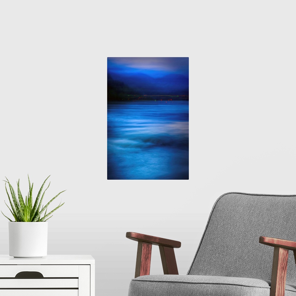 A modern room featuring A large vertical piece with majestic blue waters below and the silhoutte of the forest and mounta...