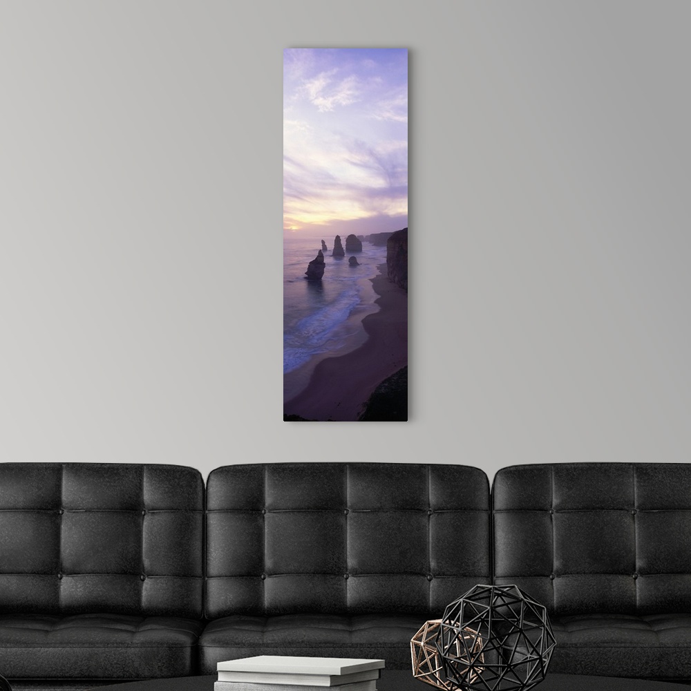 A modern room featuring Vertical panoramic photograph of shore with tall vertical rock formations in the ocean under clou...