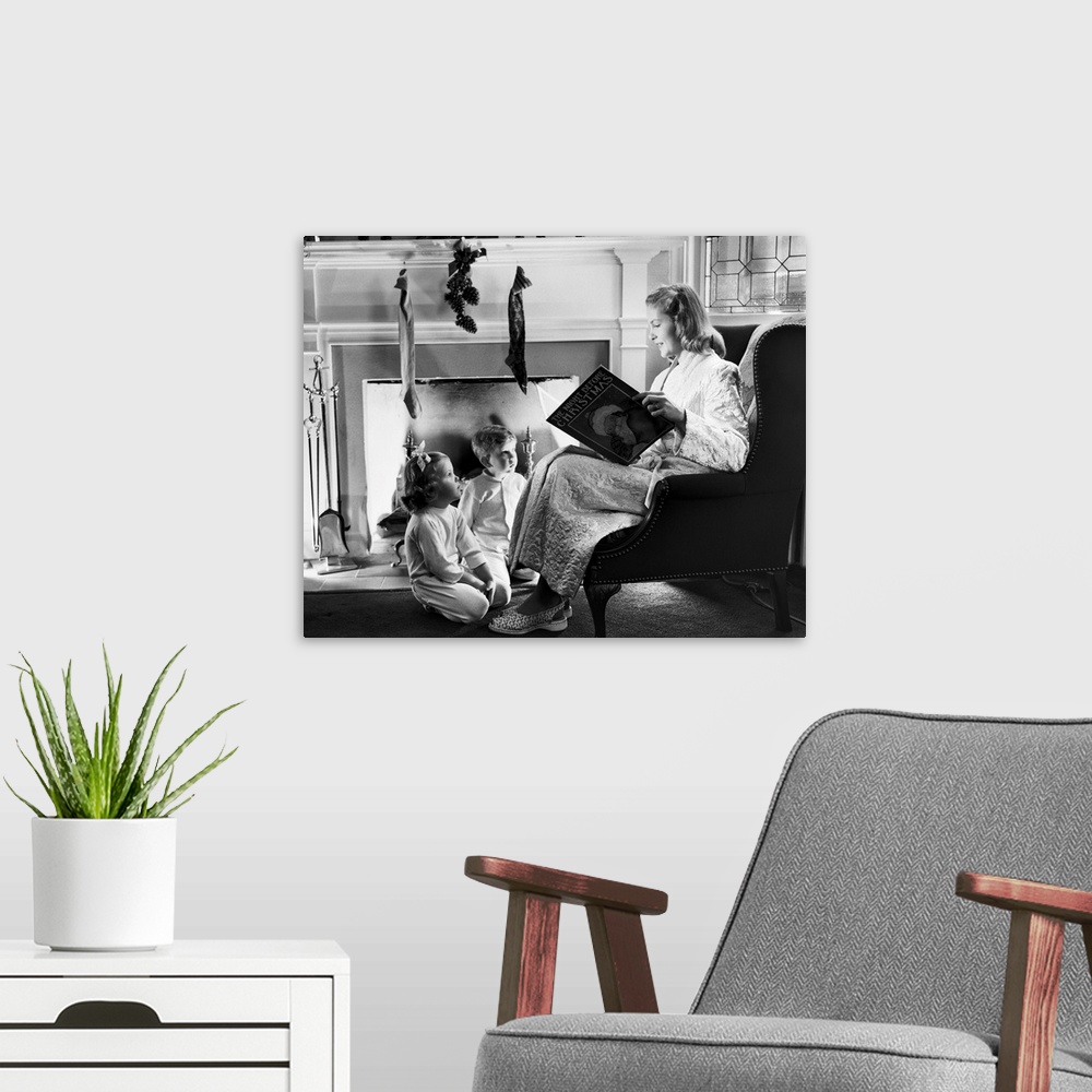 A modern room featuring 1940s 1950s Mother Reading Christmas Story To Boy Girl Sitting By Fireplace Hung With Stockings.