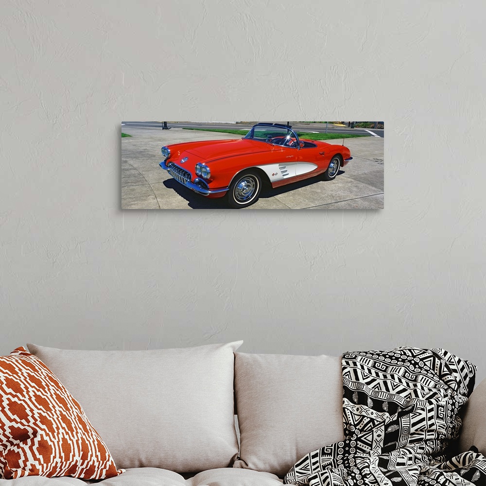 A bohemian room featuring This panoramic photograph shows a vintage muscle car convertible parked on pavement.