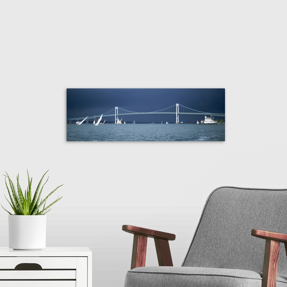 A modern room featuring Stark white suspension bridge and boats on the water contrasted against a darkening sky, sailing ...