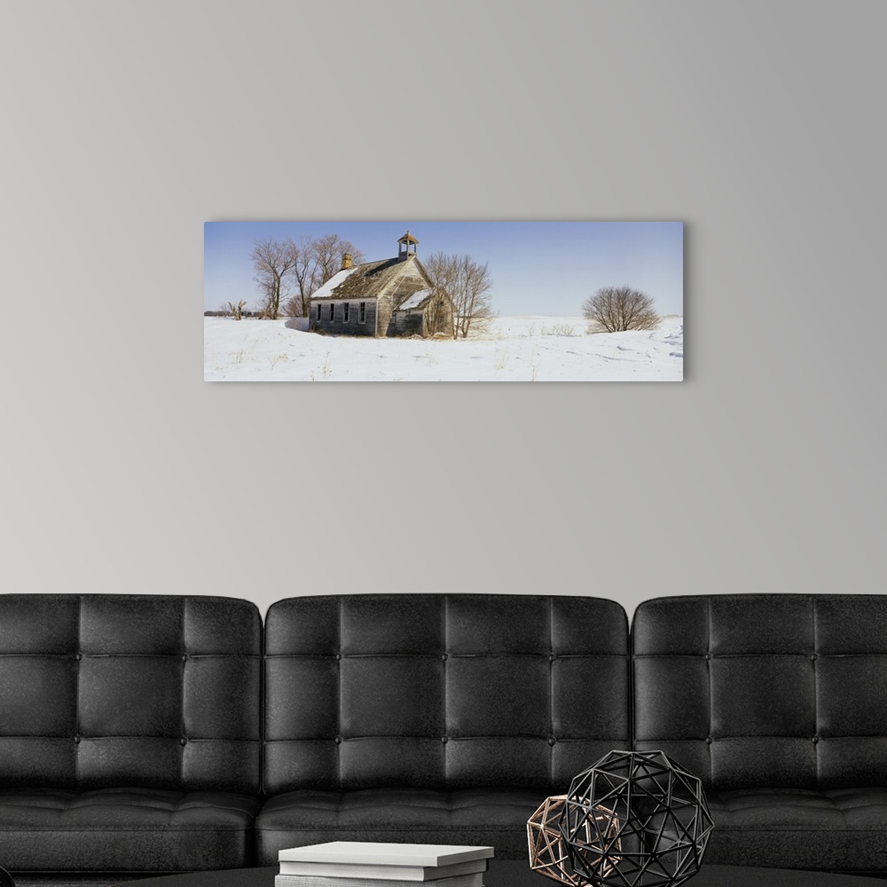 A modern room featuring A run down building is surrounded by snow covered land and bare trees.