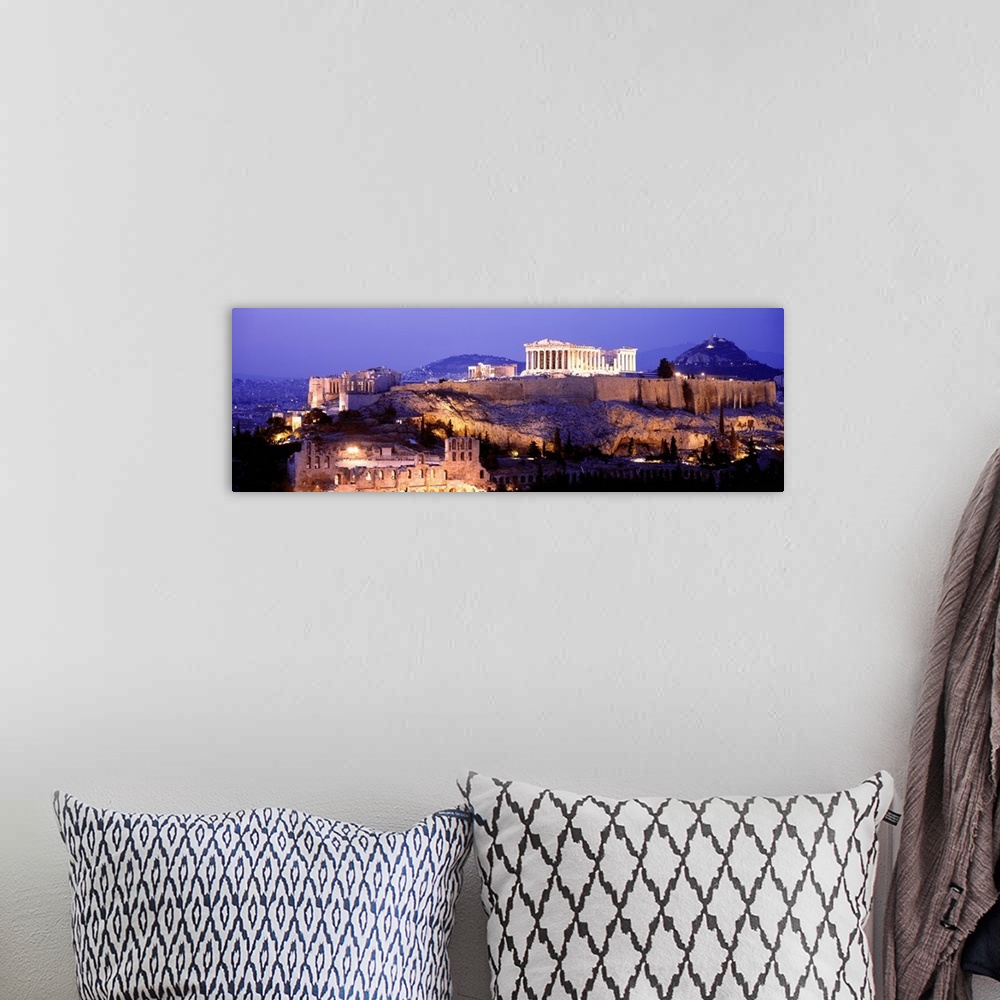 A bohemian room featuring Panoramic image of Acropolis lit up at dusk as it sits high on a hill overlooking Athens, Greece.
