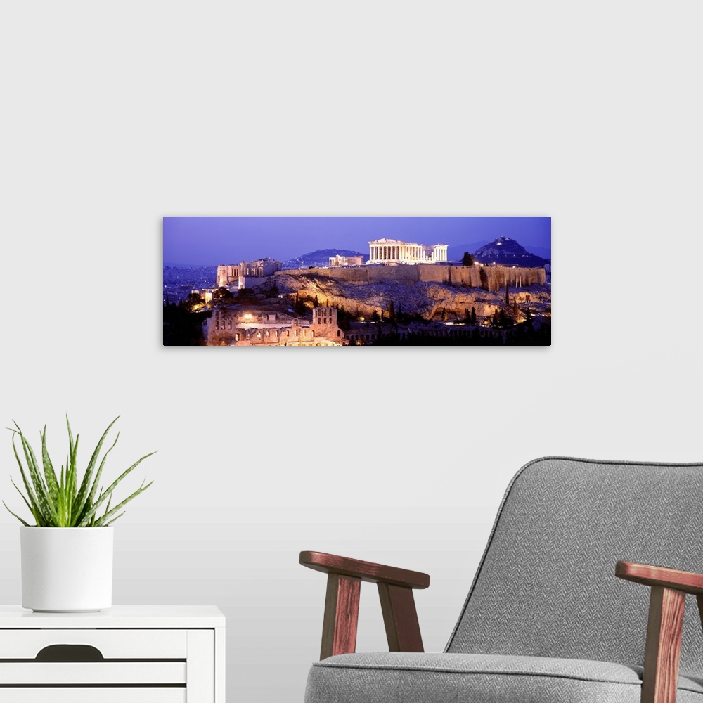 A modern room featuring Panoramic image of Acropolis lit up at dusk as it sits high on a hill overlooking Athens, Greece.