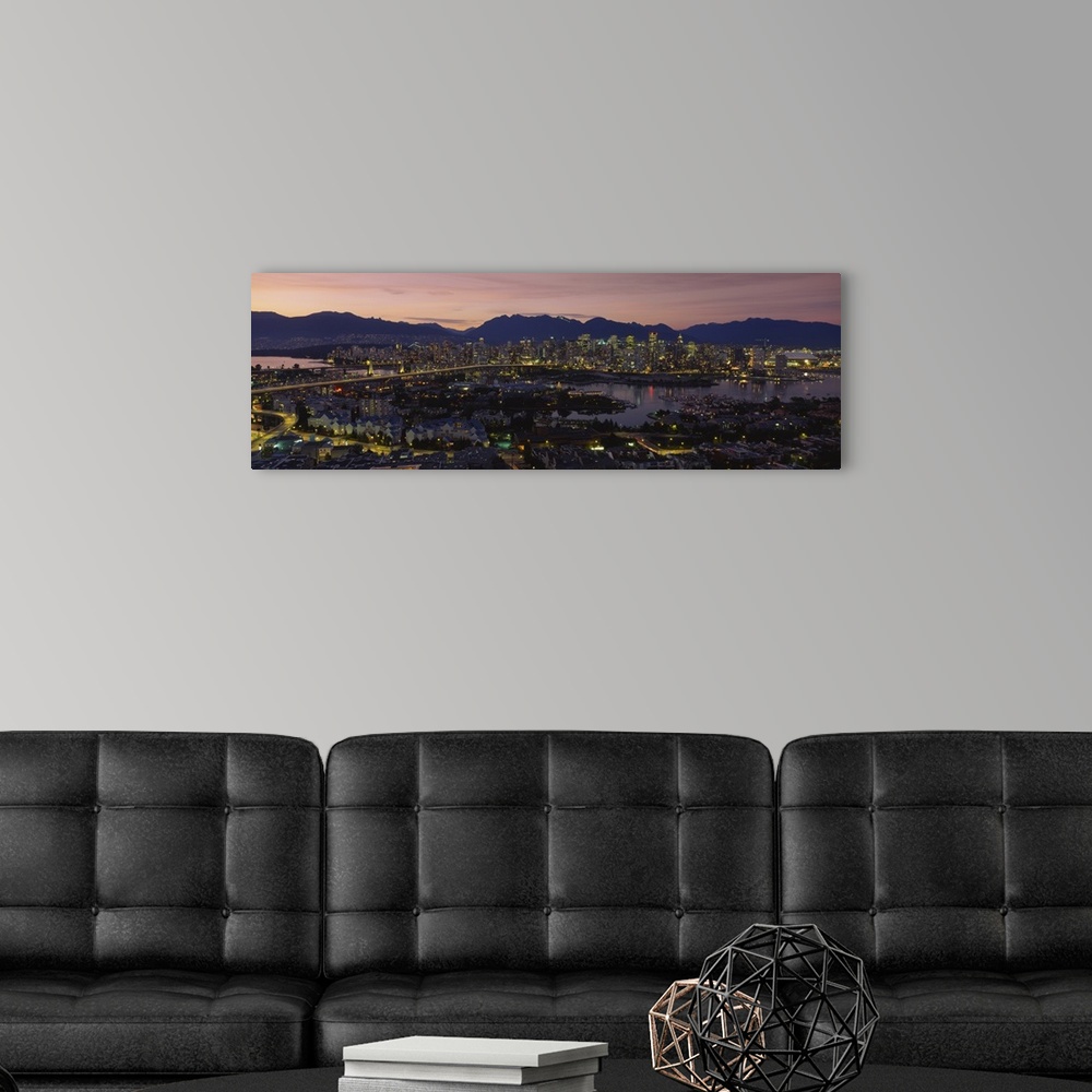 A modern room featuring Panoramic photograph of skyline and waterfront at sunset with buildings lit up and mountain silho...