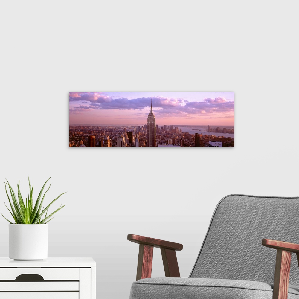 A modern room featuring Aerial panoramic picture of New York City and the top of the Empire State Building in the pink gl...