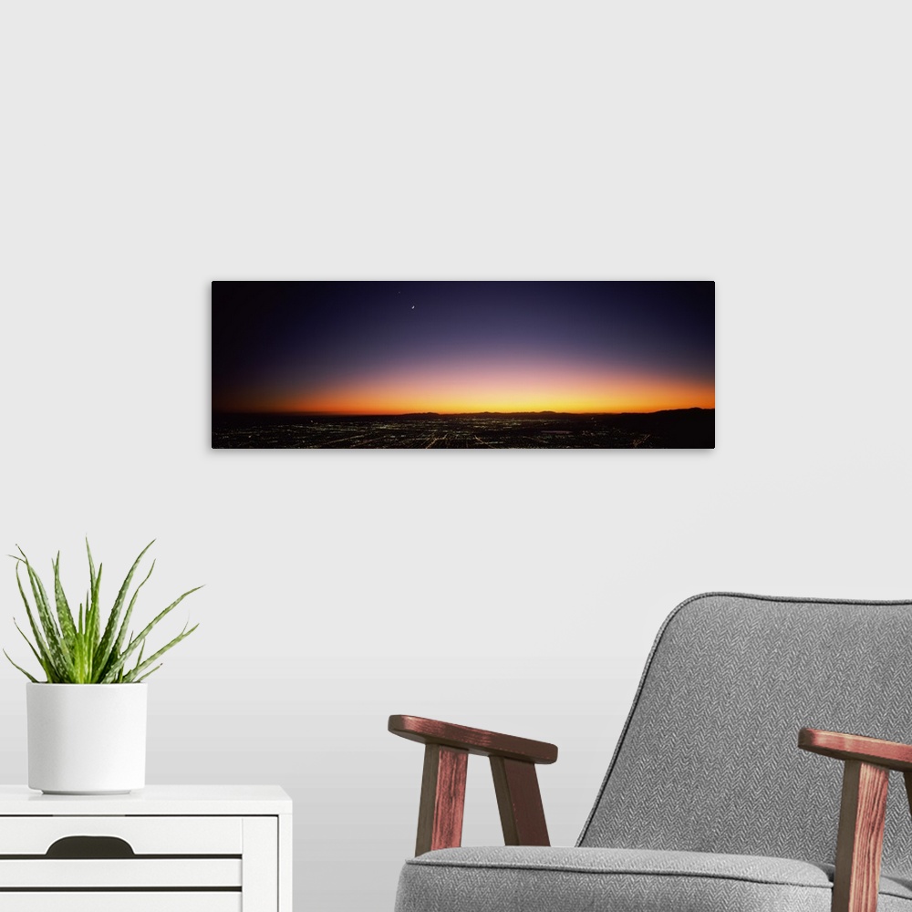 A modern room featuring An aerial photograph taken of Los Angeles at night with the sun just setting below the horizon.