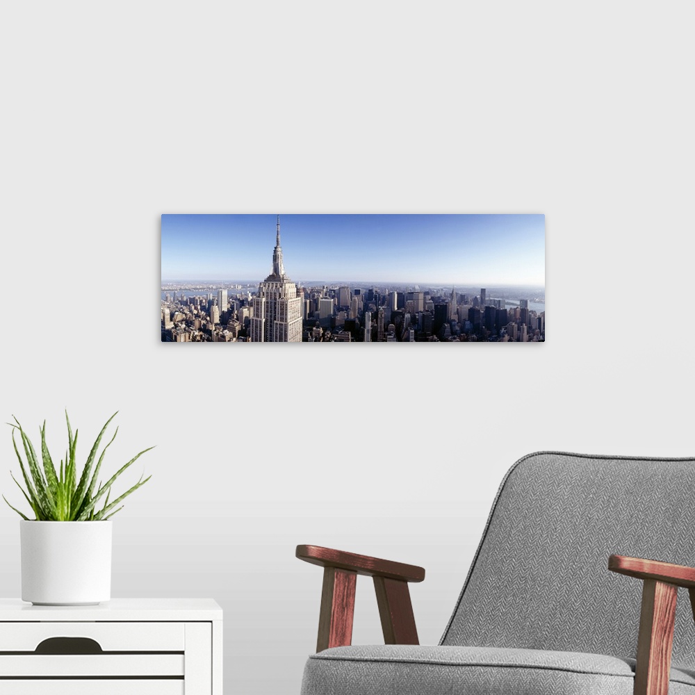 A modern room featuring A high angle photograph of the NYC skyline with the Empire State building in the foreground tower...