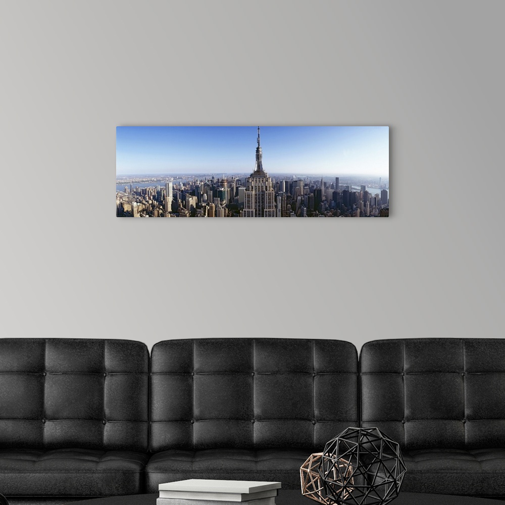 A modern room featuring Wide angle, aerial photograph of New York City beneath a blue sky, the Empire State Building in t...