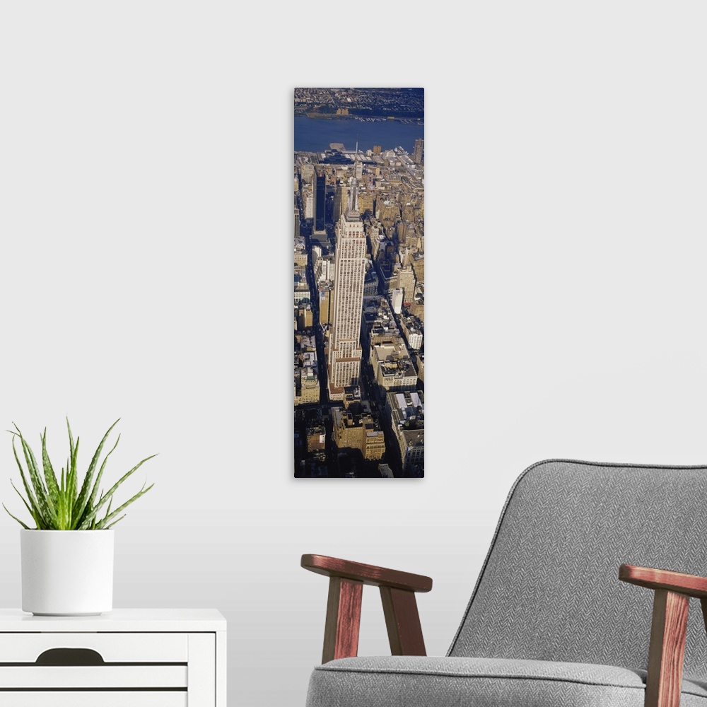 A modern room featuring A long vertical picture taken from above the Empire State building which towers over the city sur...