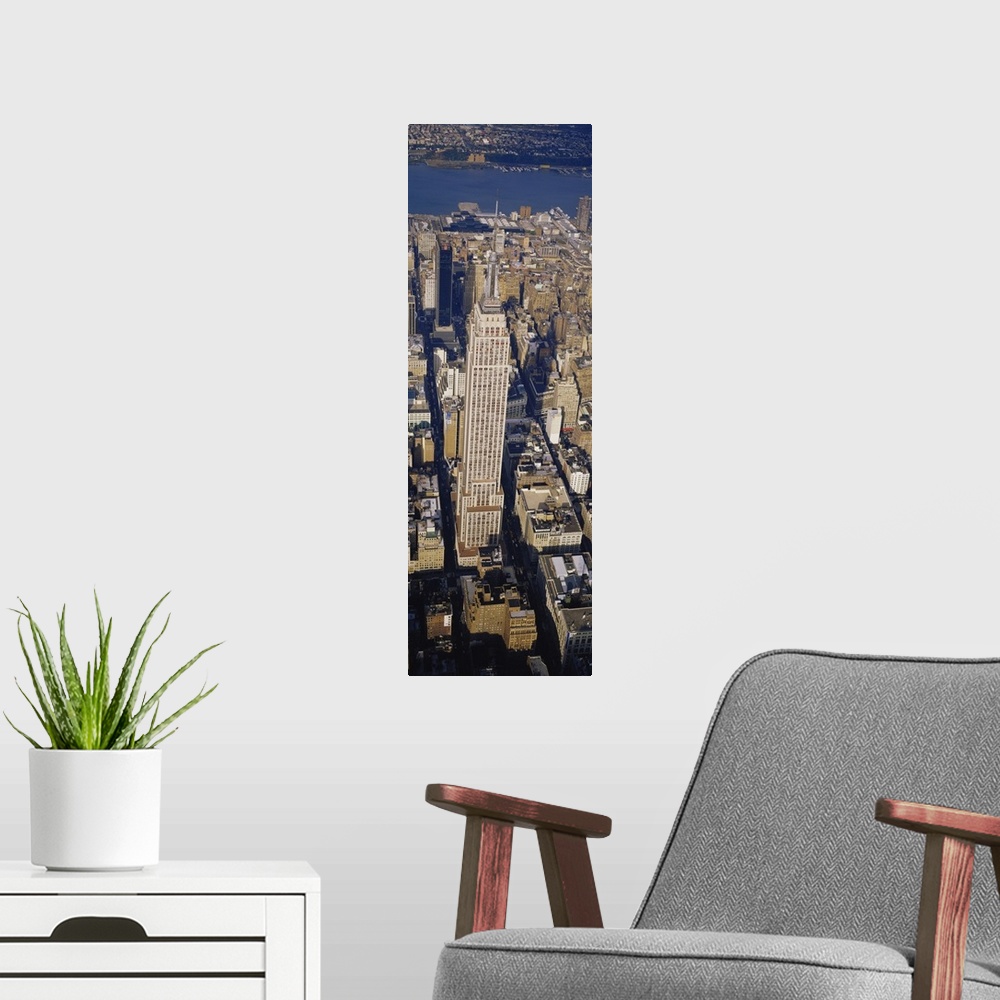 A modern room featuring A long vertical picture taken from above the Empire State building which towers over the city sur...