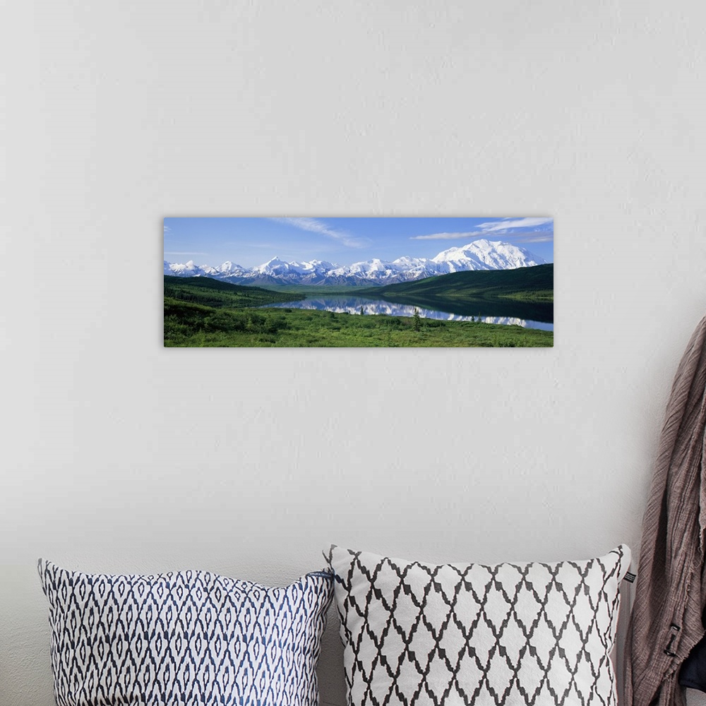A bohemian room featuring Panoramic photo of green fields surrounding a lake with snowy mountains in the distance.