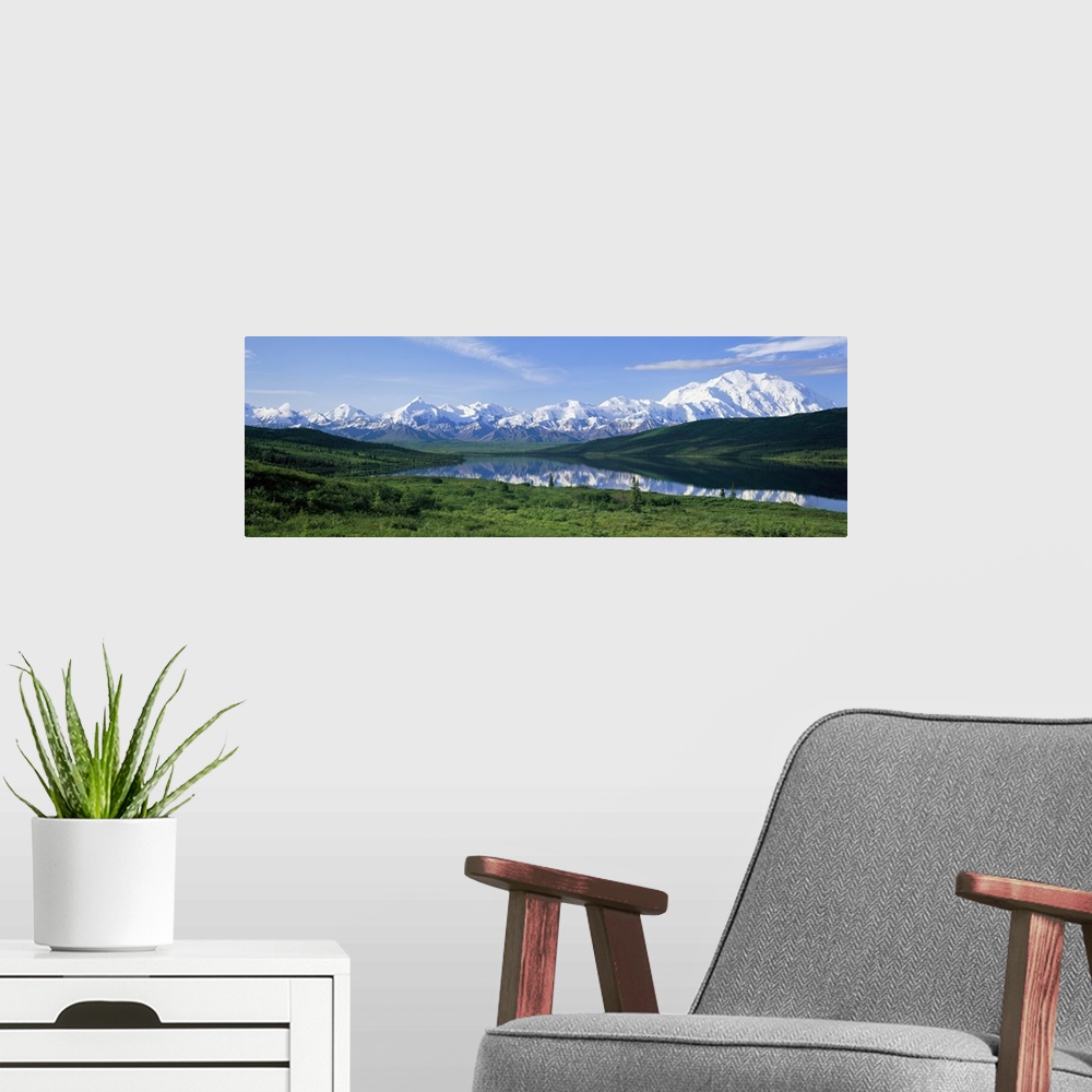 A modern room featuring Panoramic photo of green fields surrounding a lake with snowy mountains in the distance.