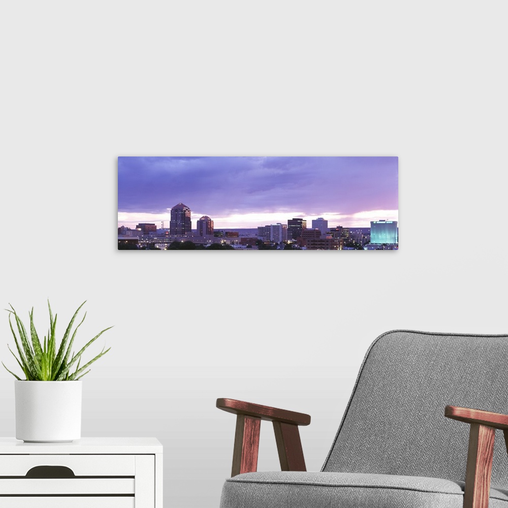 A modern room featuring Panoramic photograph on a big canvas of the Albuquerque skyline with lit skyscrapers at night, be...