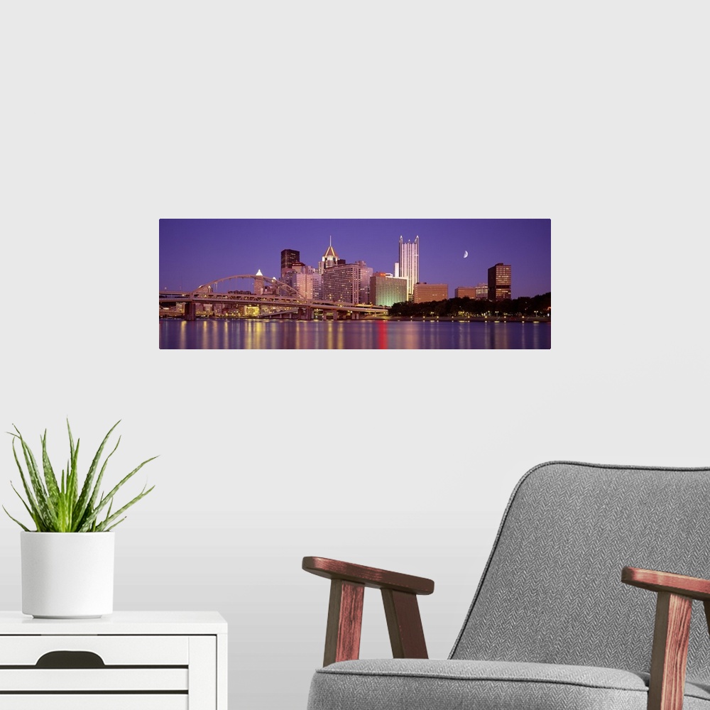 A modern room featuring Panoramic view of the bridge and city buildings in Pittsburgh, Pennsylvania, at night, with blurr...