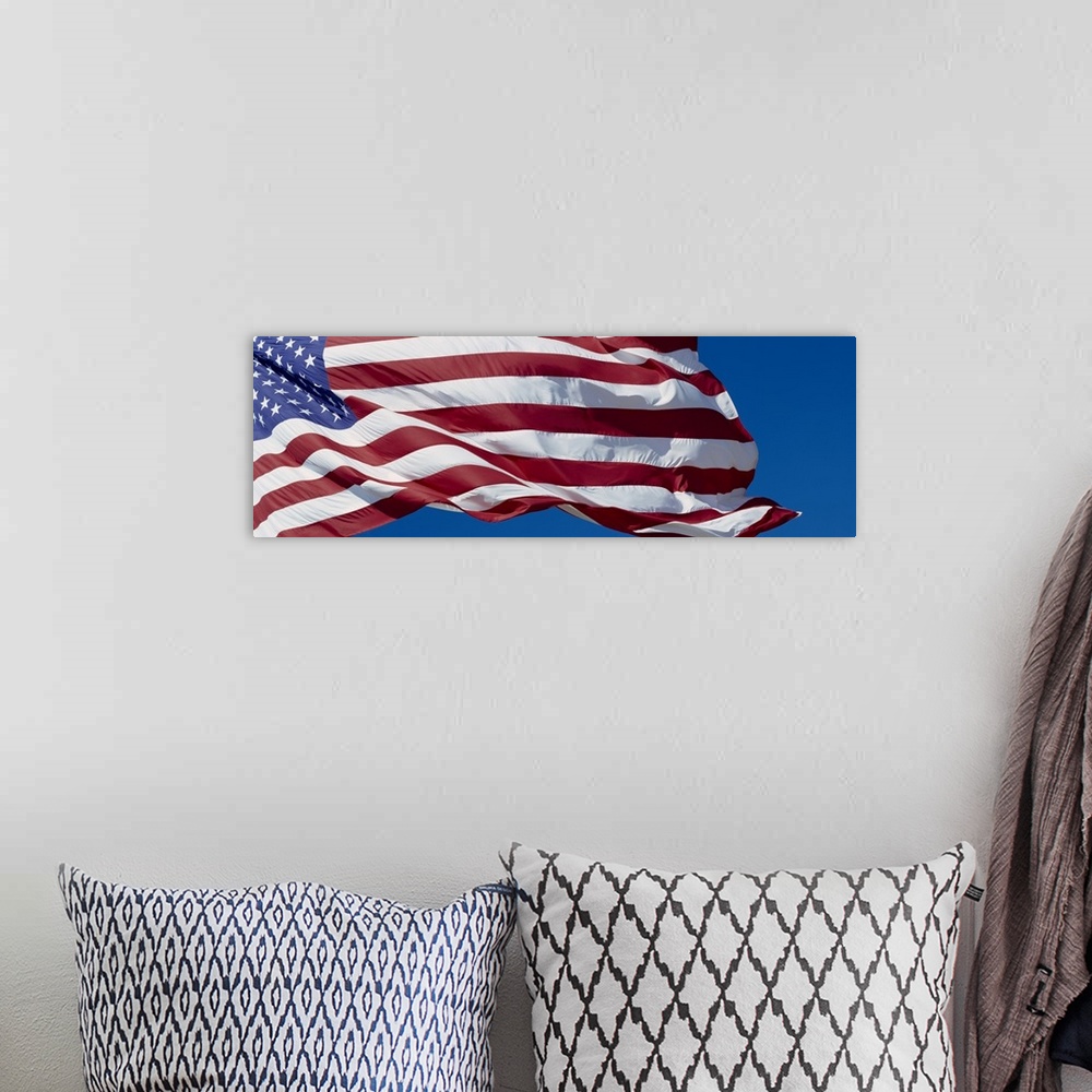 A bohemian room featuring Old Glory billowing in the wind on a bright day, with a clear blue sky in the background.