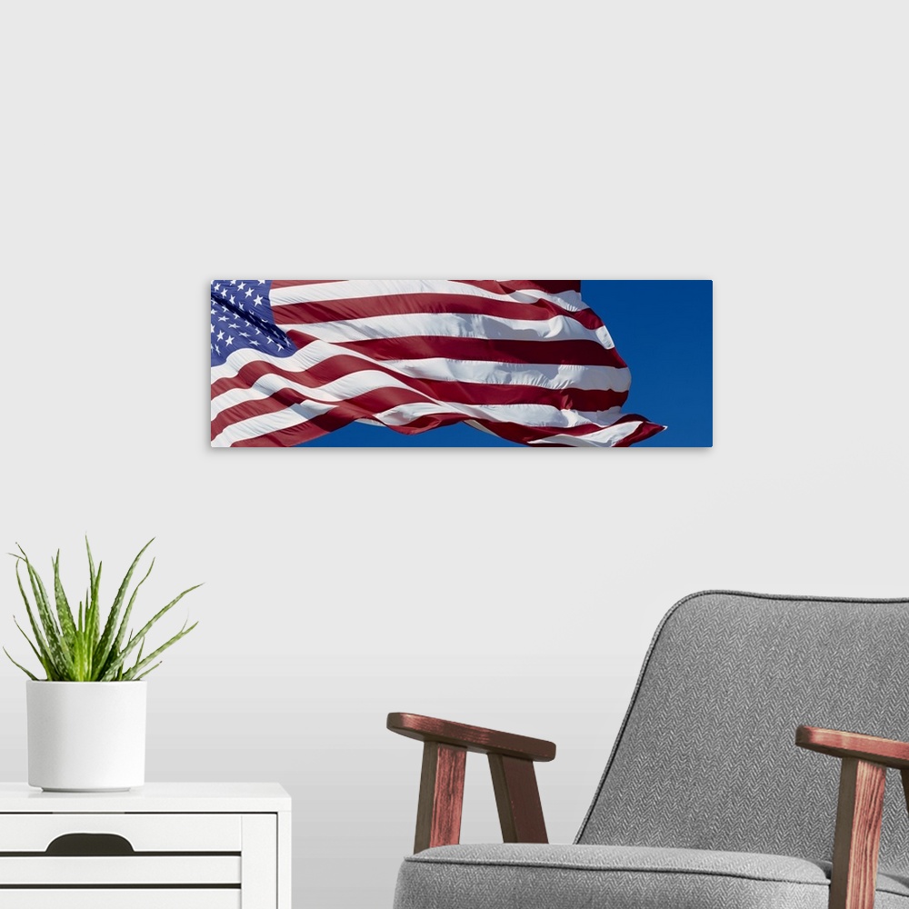 A modern room featuring Old Glory billowing in the wind on a bright day, with a clear blue sky in the background.