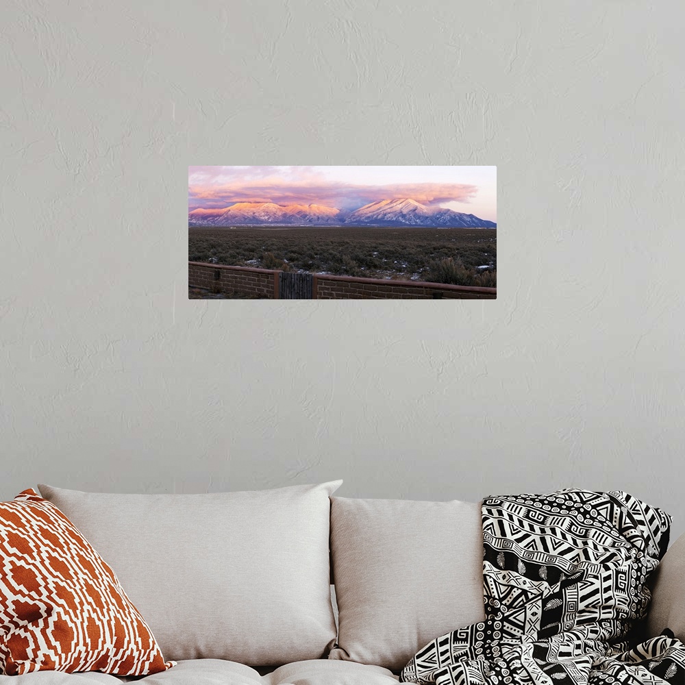 A bohemian room featuring Mountain range viewed from an adobe brick wall and Sangre De Cristo Mountains, New Mexico, USA.