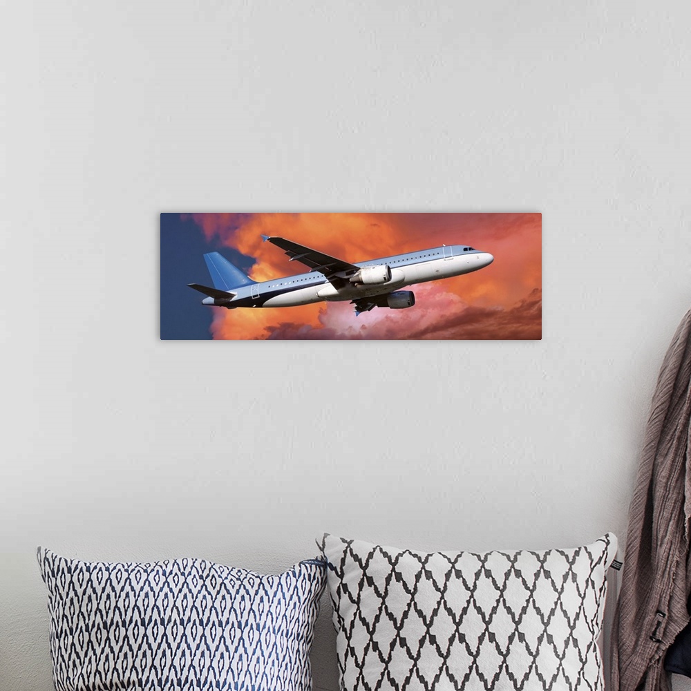 A bohemian room featuring This large panoramic picture is of a commercial airplane ascending into warm toned clouds.