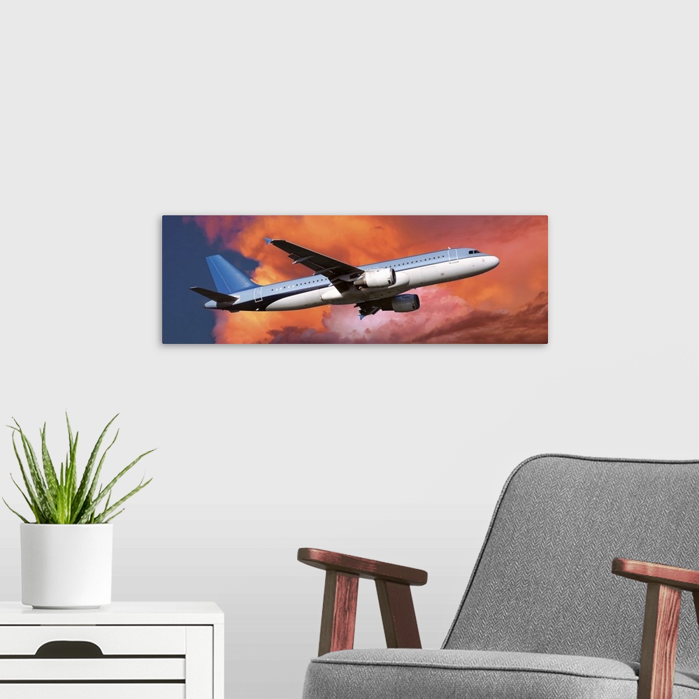 A modern room featuring This large panoramic picture is of a commercial airplane ascending into warm toned clouds.