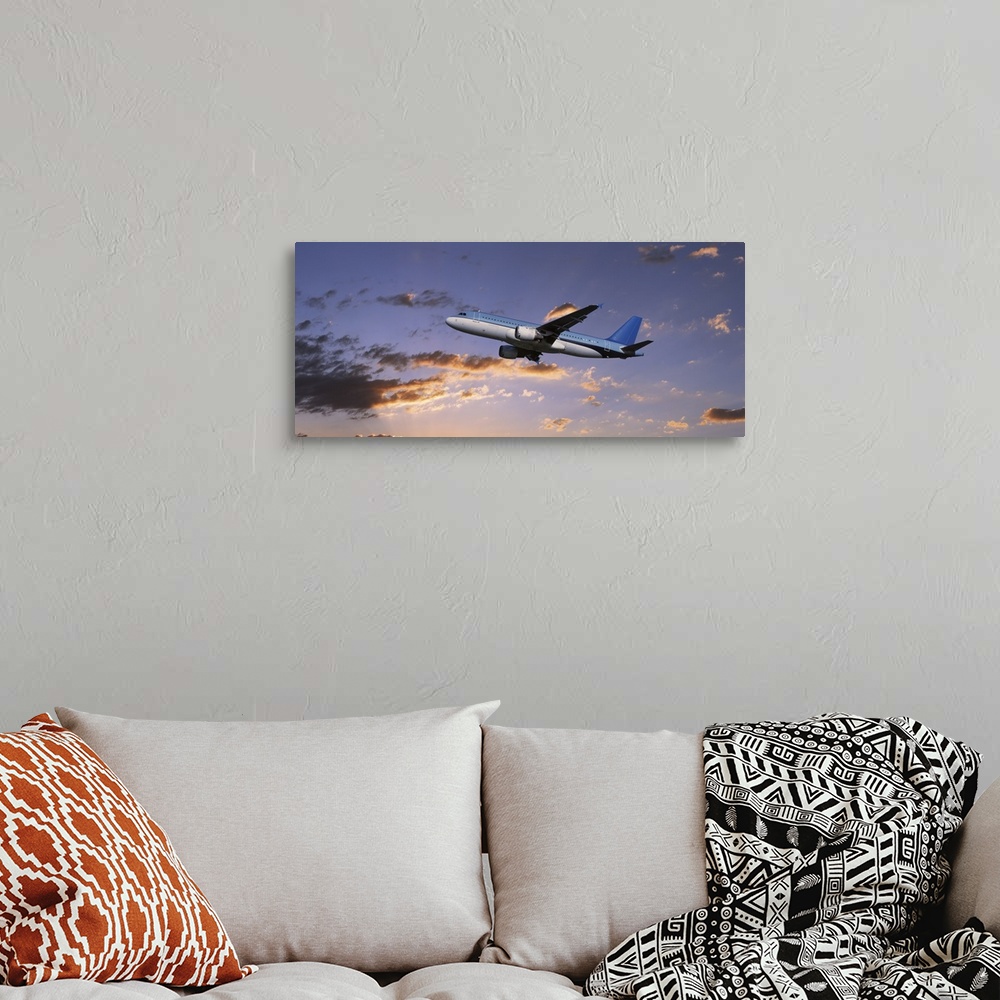 A bohemian room featuring A commercial airplane is pictured from below as it soars through a sunset lit sky.