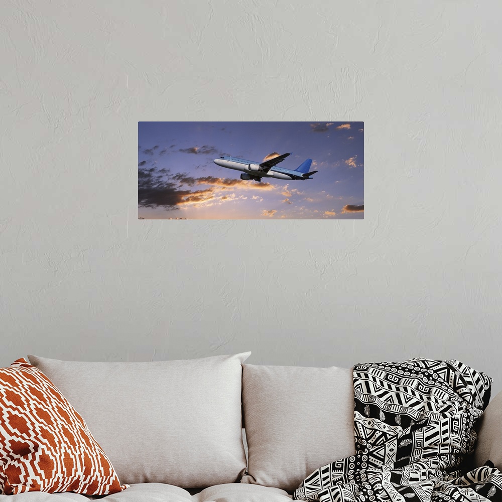 A bohemian room featuring A commercial airplane is pictured from below as it soars through a sunset lit sky.