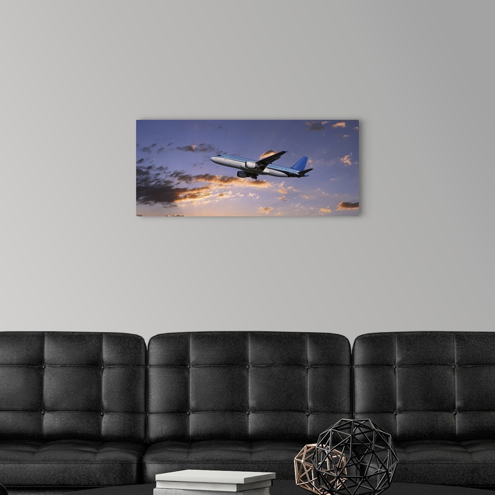 A modern room featuring A commercial airplane is pictured from below as it soars through a sunset lit sky.