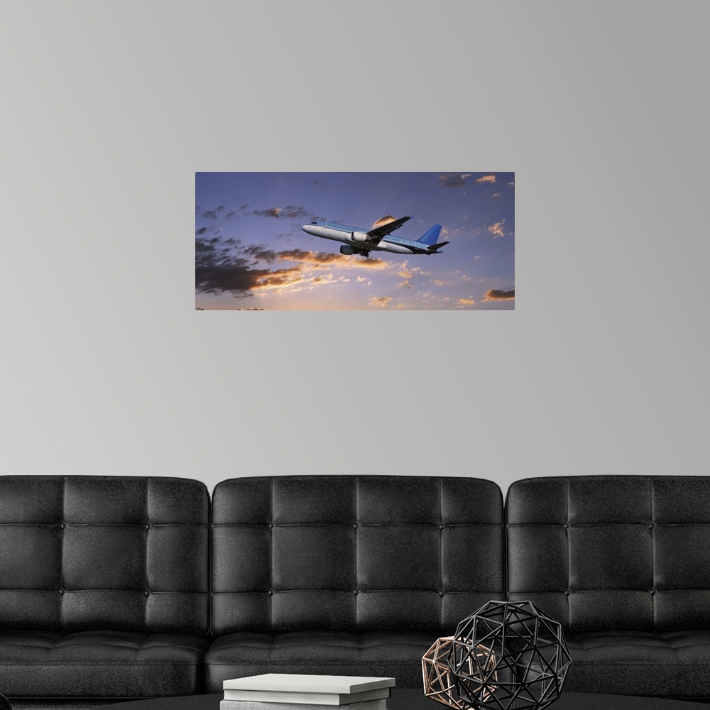 A modern room featuring A commercial airplane is pictured from below as it soars through a sunset lit sky.