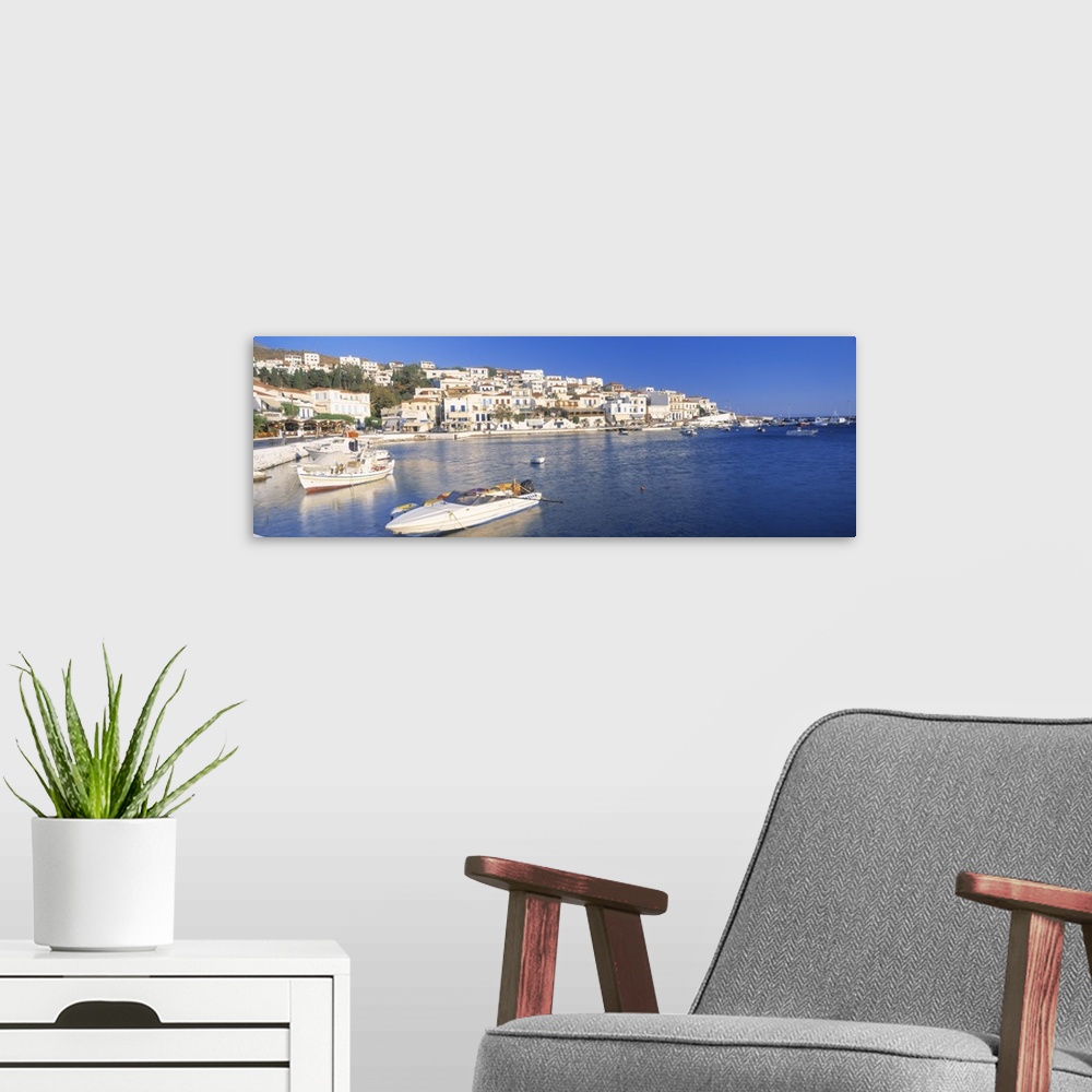 A modern room featuring Houses in Greece are photographed from across the water where several boats sit docked.