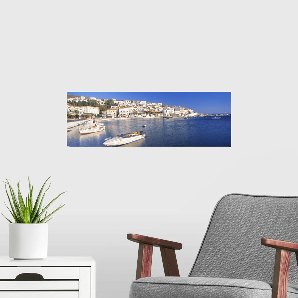 A modern room featuring Houses in Greece are photographed from across the water where several boats sit docked.