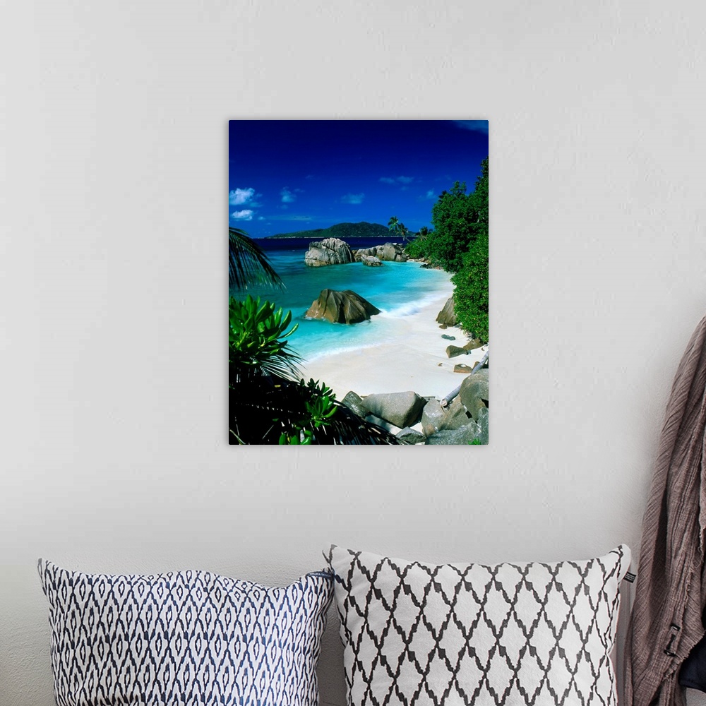 A bohemian room featuring This is vertical photograph of a beach landscape framed by tropical foliage with massive boulders...