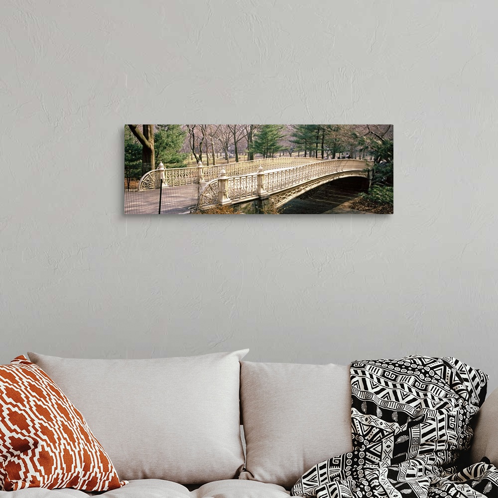 A bohemian room featuring A walking bridge is photographed from the side with a view of the park just behind it.