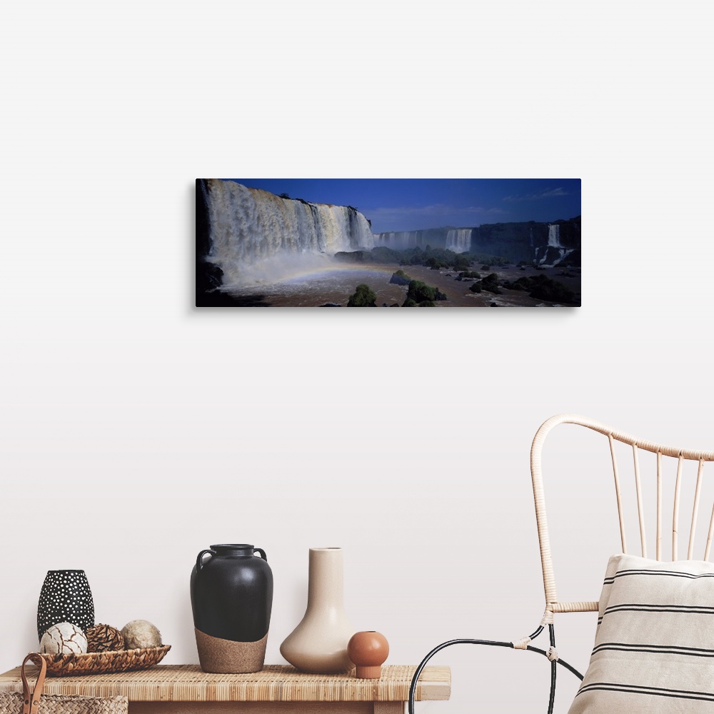 A farmhouse room featuring This is a panoramic photograph of enormous South American waterfalls and a rainbow forming under ...