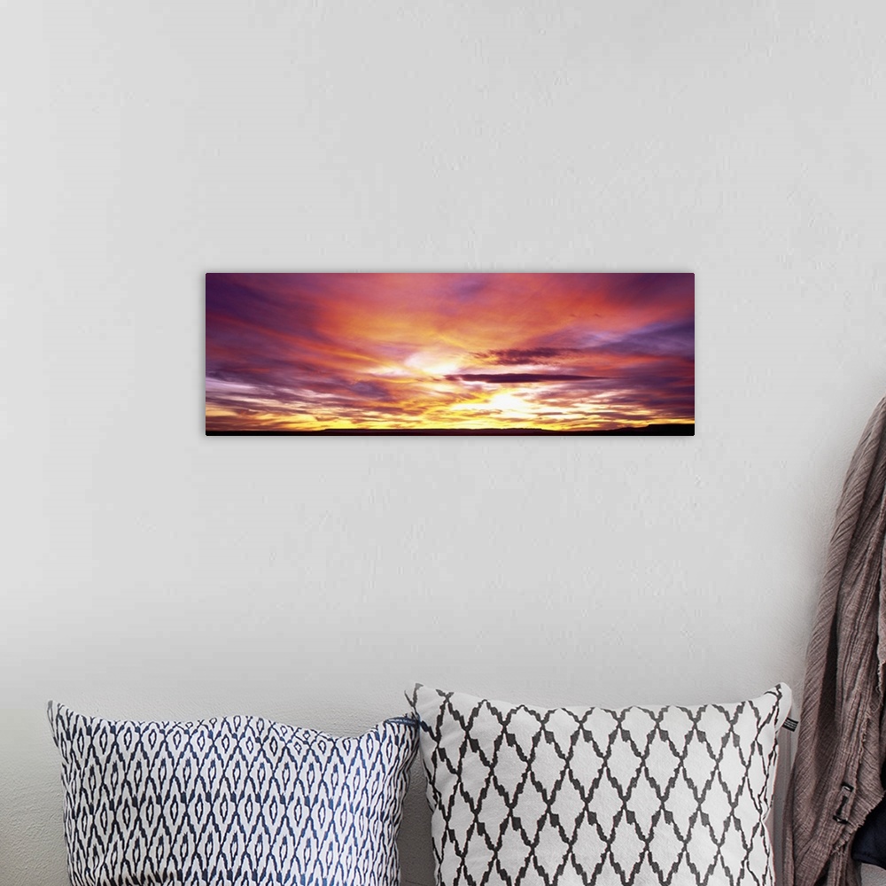 A bohemian room featuring A panoramic photograph of clouds lit up in brilliant colors from the sun below the horizon.