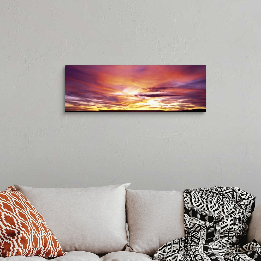 A bohemian room featuring A panoramic photograph of clouds lit up in brilliant colors from the sun below the horizon.
