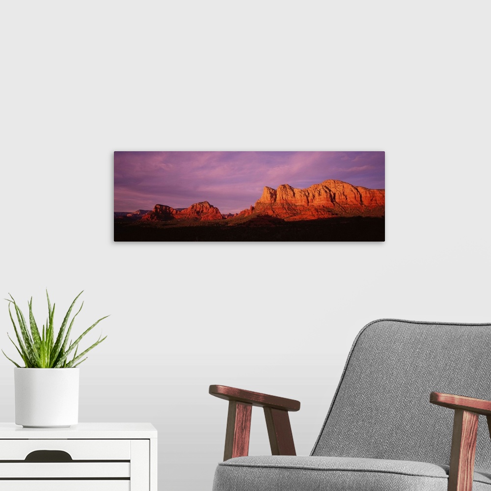 A modern room featuring This photograph is a panoramic wall hanging that captures the fading light illuminating the deser...