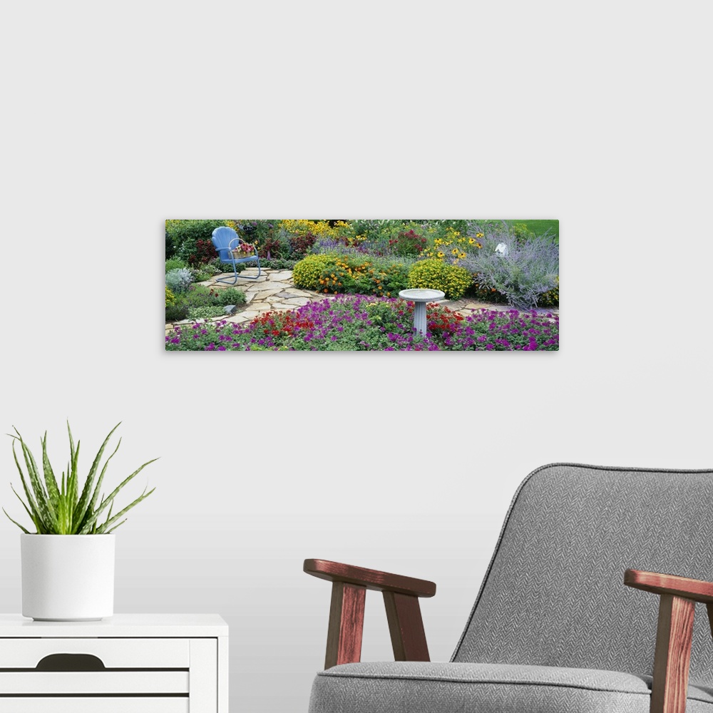 A modern room featuring Oversized, horizontal photograph of many types of vibrant flowers and green foliage in a flower g...