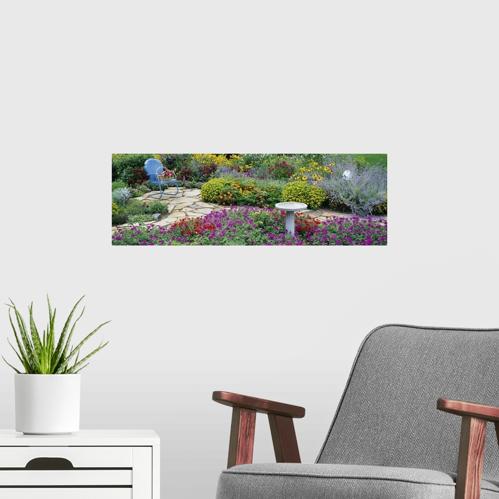 A modern room featuring Oversized, horizontal photograph of many types of vibrant flowers and green foliage in a flower g...