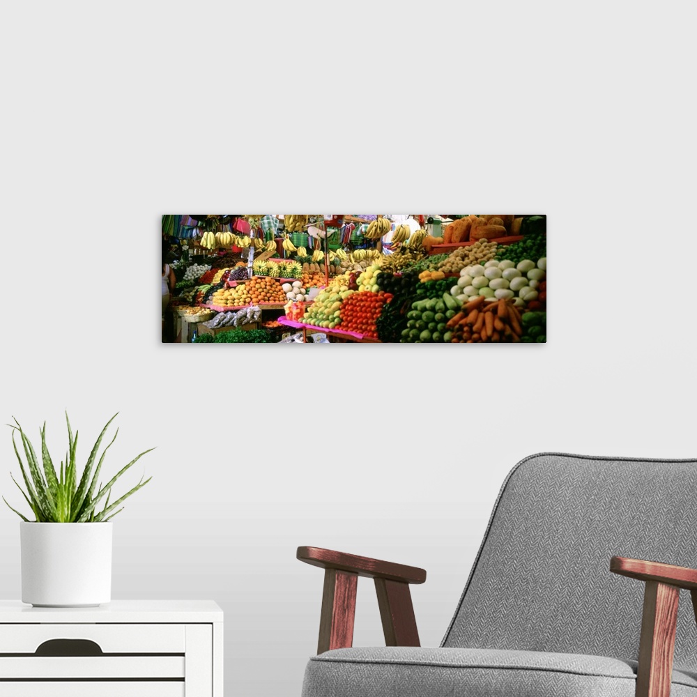 A modern room featuring Tables full of freshly harvested food, including carrots, bananas, corn, apples, and tomatoes, as...