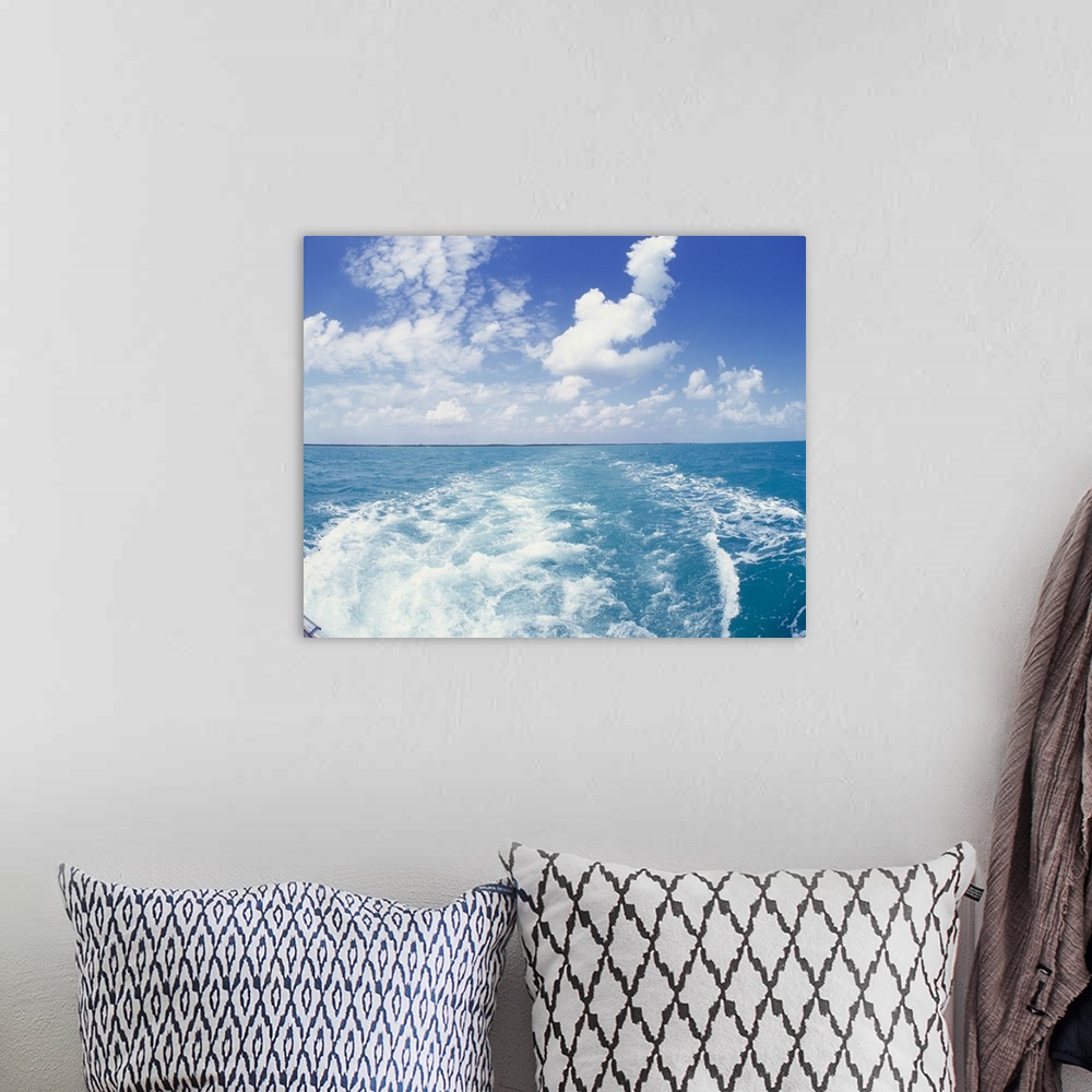 A bohemian room featuring Photo on canvas of the ocean with land in the far distance and puffy clouds above looking from be...