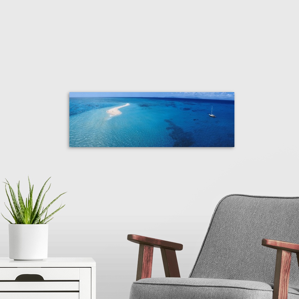 A modern room featuring Panoramic, aerial photograph of clear blue waters over the Great Barrier Reef, a single sailboat ...