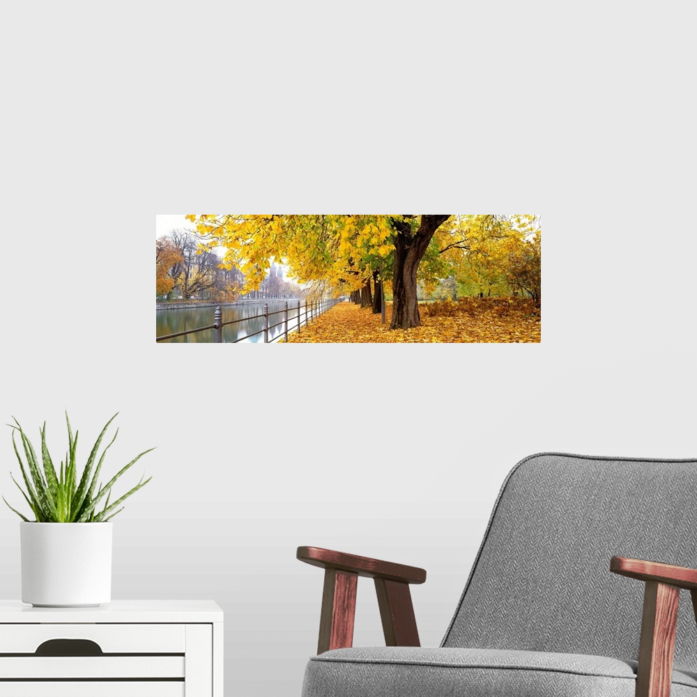A modern room featuring Large panoramic photograph of city riverbank in Munich, Germany as fall/autumn turns to winter an...