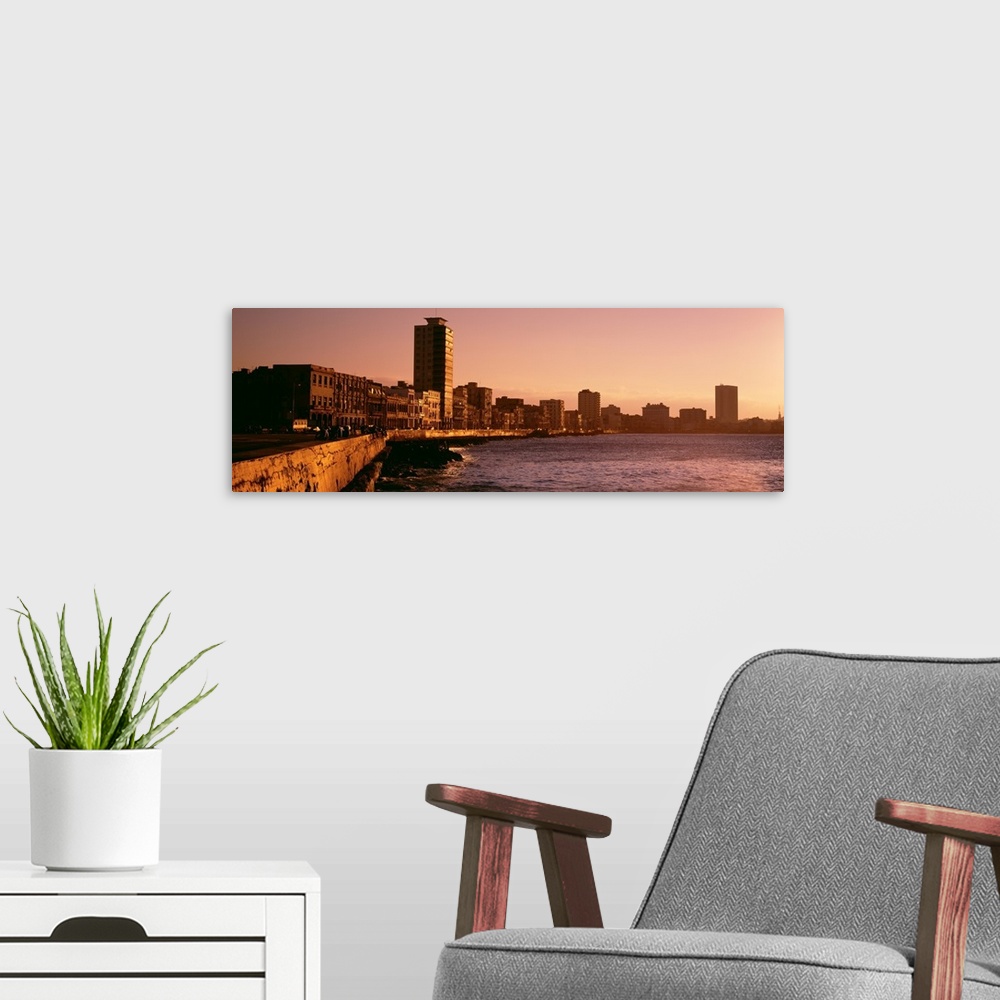 A modern room featuring This wide angle picture is taken of buildings lining a body of water in Havana Cuba during sun down.